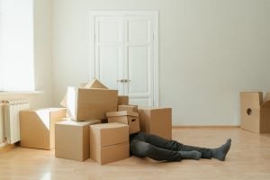 a person lying beyond several moving boxes before calling expert moving crews to help him