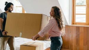 two people carrying a large cardboard box