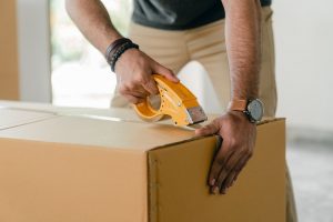 a person wearing a watch taping a moving box before the relocation