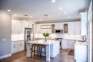 A kitchen with a dining space, chairs, cupboards, and kitchen appliances