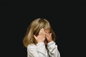 A distressed little girl covering her face with hands