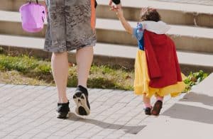 A father going trick-or-treating with his daughter.