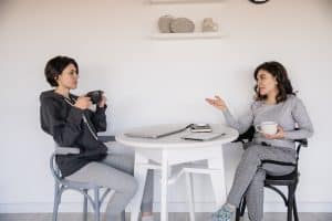 two female friends talking top each other with a cup of cofee in their hands discussing whether to trust moving reviews