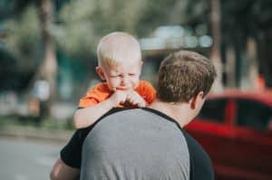 A father carrying his crying son.