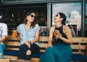 Two friends laughing over drinks.