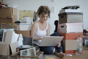 female typing on the laptop with cardboard boxes around