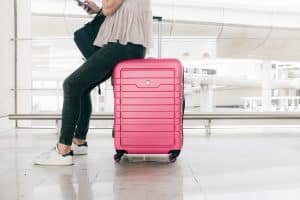 woman sitting on a pink suitcases