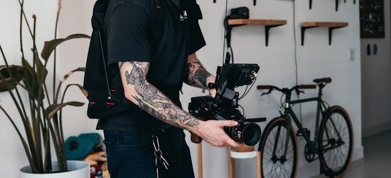 Man in Black T-shirt and White Cap Holding Black Video Camera