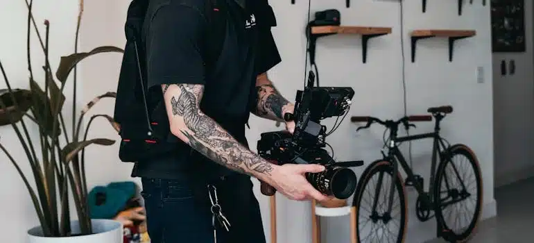 Man in Black T-shirt and White Cap Holding Black Video Camera