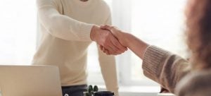 A mover and a woman shaking hands before she decides to move antique furniture with his help 