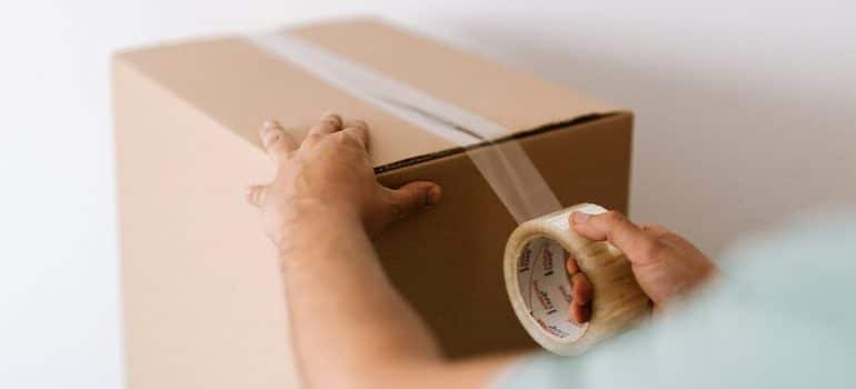 A person taping a box after learning what packing supplies should you use