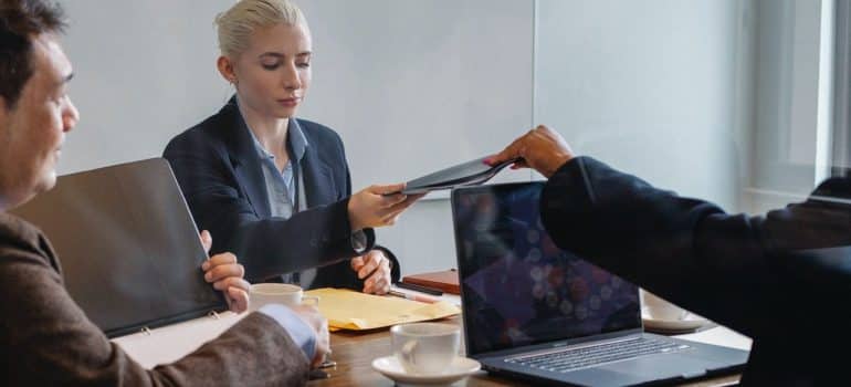 a man handing a file to a woman across the desk