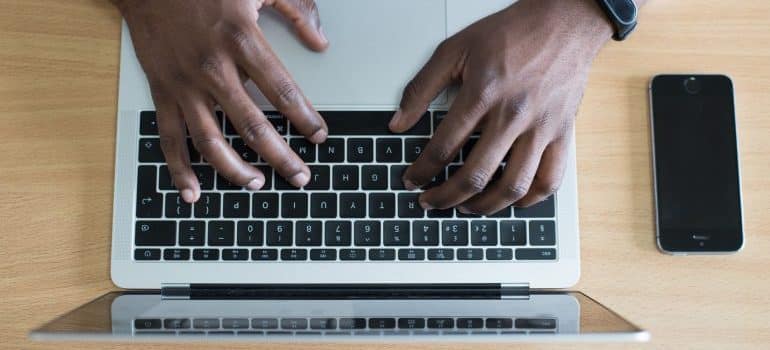 Human hands typing on the keyboard of a laptop, which is on the desk