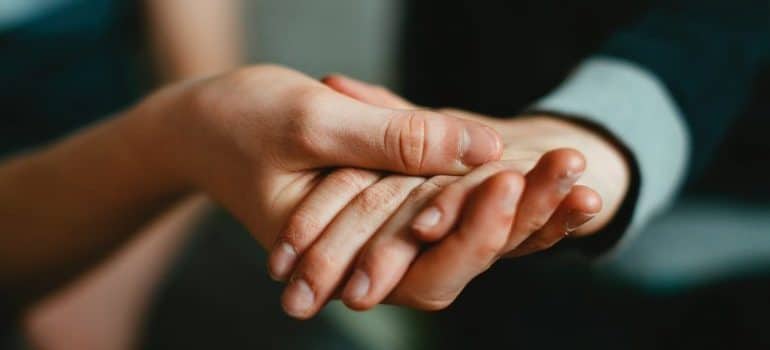 Hand holding another hand in terms of assisting while moving a business overseas 