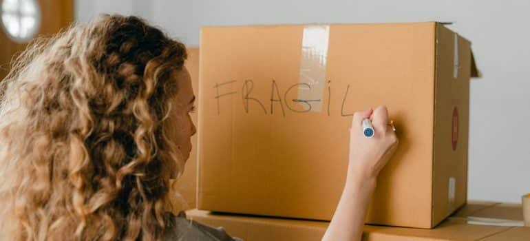 Woman writing fragile on a box