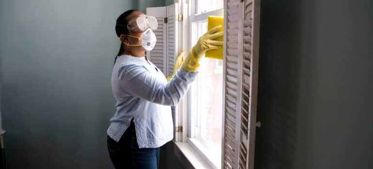 A woman cleaning windows with all equipment needed for spring cleaning before and after moving 