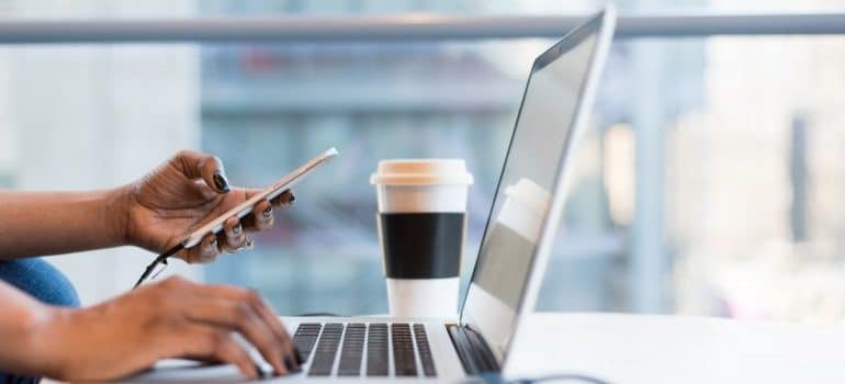 Laptop on the desk, and phone in a ladies hand, ready to research 