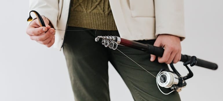 A man holding a fishing rod preparing to pack fishing equipment for an interstate move