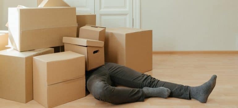 man laying on the floor with a bunch of boxes on top of him