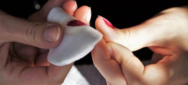 a woman removing her red nail polish