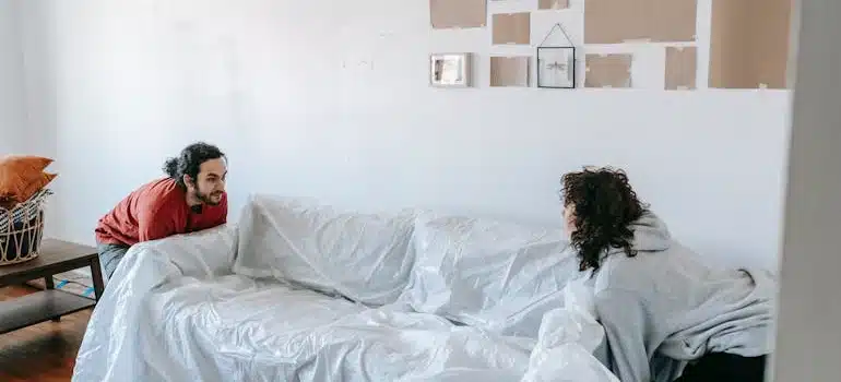 A Couple Lifting A Sofa talk about whether to rent a truck or hire movers