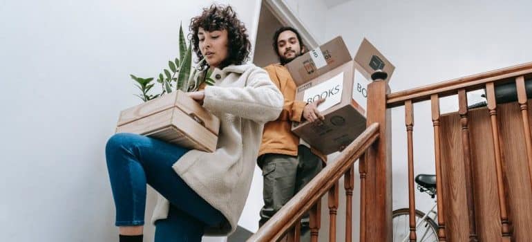 man and woman on the stairs carrying full boxes