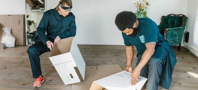 Two movers preparing Cardboard Boxes