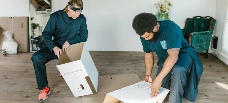Two movers preparing Cardboard Boxes