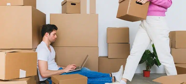 A man sitting amid boxes browsing on his laptop how to declutter office for a move