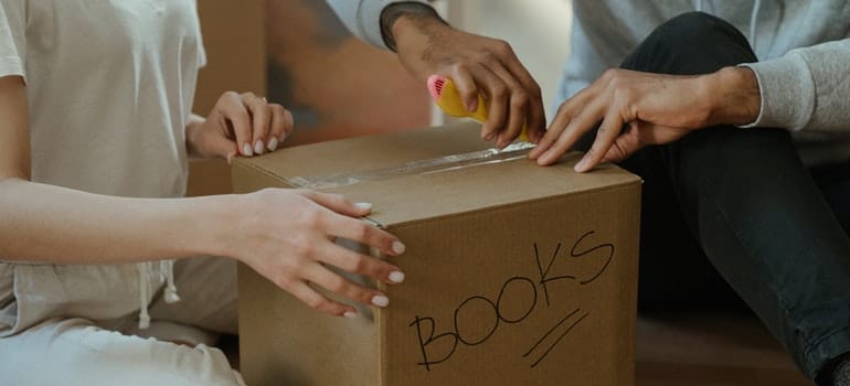 People taping a box before moving a library in Miami.