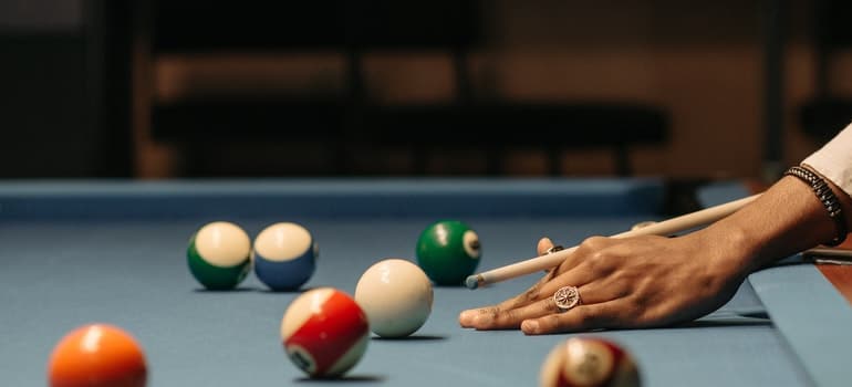 A person playing on the pool table after they hire professionals when moving a pool table