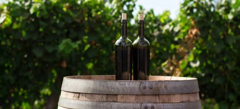 Two wine bottles on a barrel, is a field