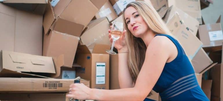 After moving your wine collection in North Miami, a woman is posing in front of boxes with a wine glass in her hands.