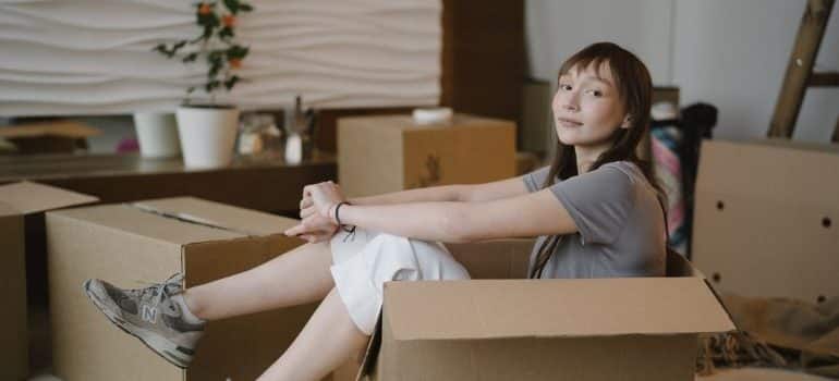 Women sitting in a moving box, thinking about moving house during bad weather