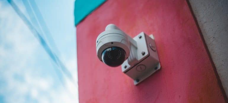 A security camera on a pink wall
