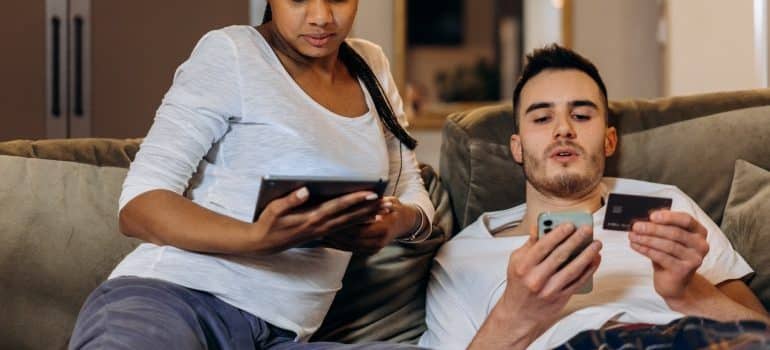 Man holding a phone and a credit card while sitting on a couch