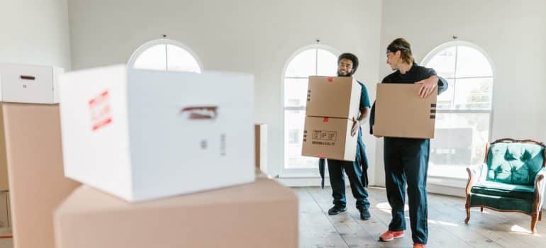 Two men carrying moving boxes as White glove movers in Miami