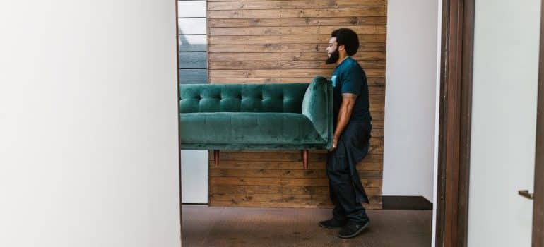 Man carrying a green sofa