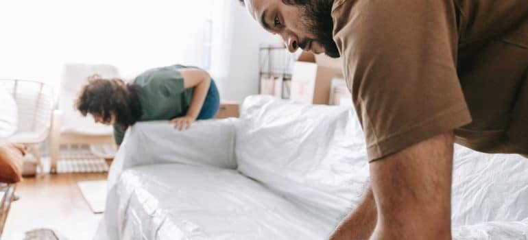 Two men wrapping a couch