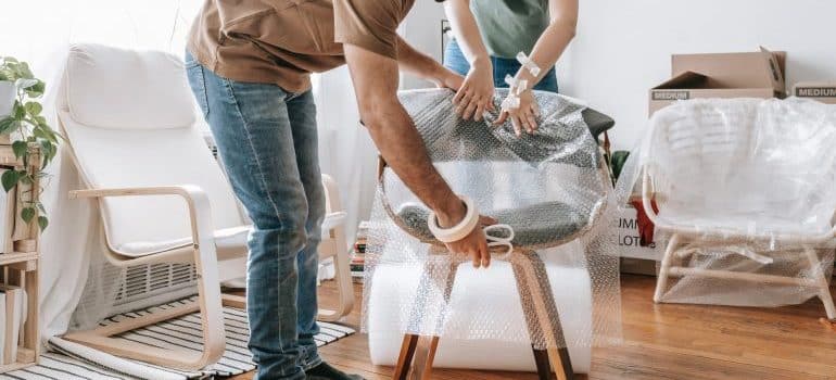 Man and woman wrapping a chair with bubble wrap
