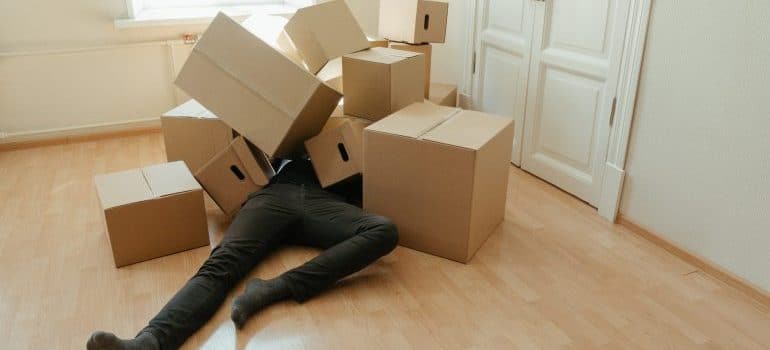 A man under the pile of moving boxes