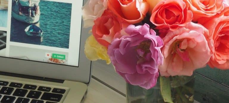 laptop and vase with flowers on a table 
