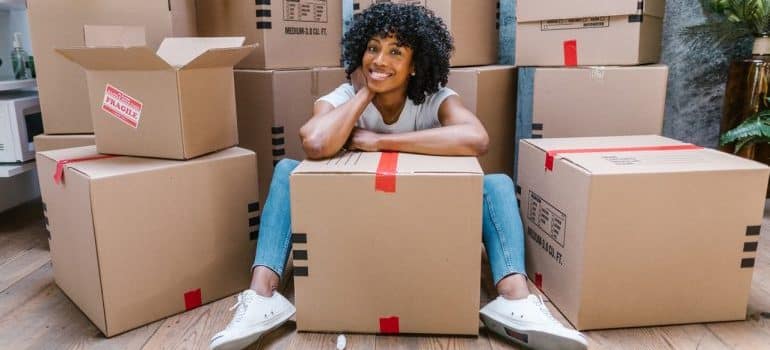 A girl surrounded by moving boxes feeling happy for choosing luxury moving solutions in Miami