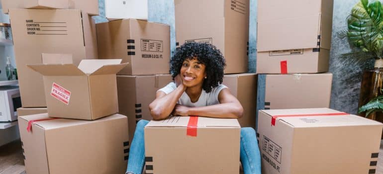 Woman sitting surrounded with packing supplies for packing and moving bulky items to Midtown Miami