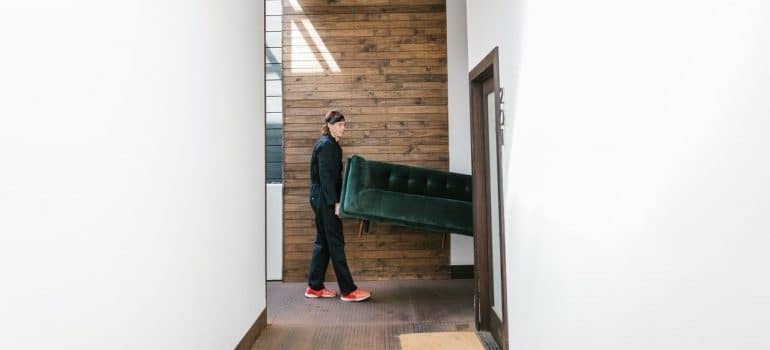 Professional movers taking sofa out of the room