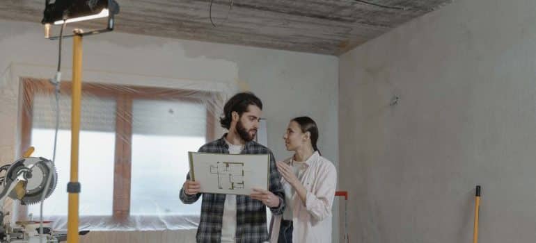 A couple holding a blueprint of the house - buy a fixer-upper in Miami