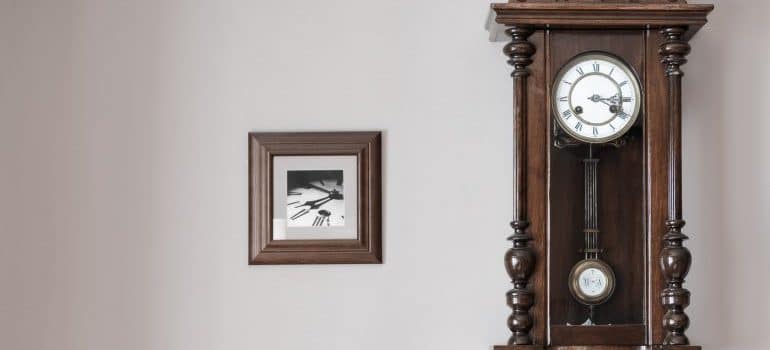 a big antique clock and a framed photograph of a clock hanging on the wall 
