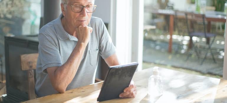 An older man is looking at a tablet.