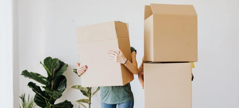 Two person holding cardboard moving boxes