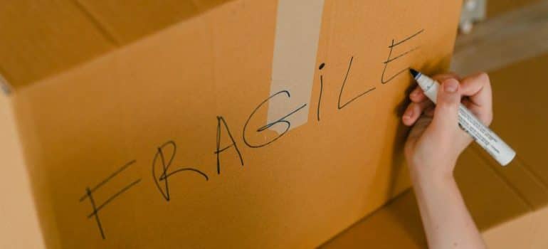 Person writing fragile on a box